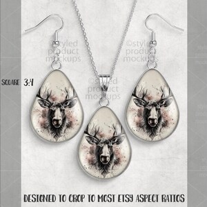 May include: A silver-toned jewelry set featuring a pendant necklace and matching earrings. Each piece has a teardrop-shaped design with a detailed illustration of a deer's head in shades of black, white, and pink. The set is designed to fit most Etsy aspect ratios.