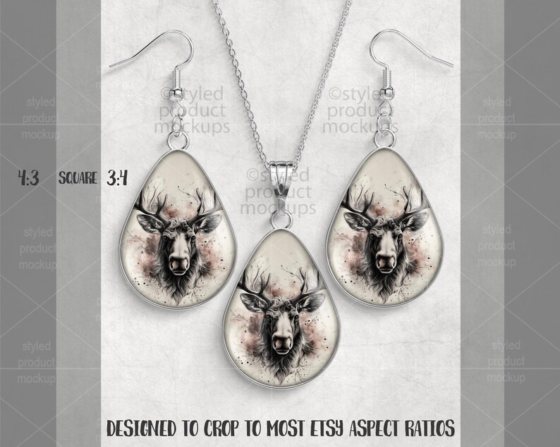 May include: A silver-toned jewelry set featuring a pendant necklace and matching earrings. Each piece has a teardrop-shaped design with a detailed illustration of a deer's head in shades of black, white, and pink. The set is designed to fit most Etsy aspect ratios.