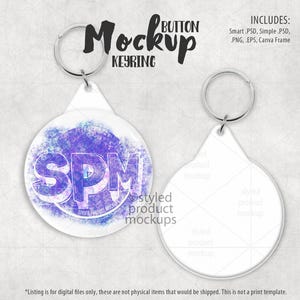 Könnte beinhalten: Ein Mockup eines runden Knopf-Schlüsselanhängers mit weißem Hintergrund und einem violetten und blauen Aquarell-Design. Das Design enthält die Buchstaben "SPM" in einer stilisierten Schriftart. Das Mockup enthält eine leere Version des Schlüsselanhängers.