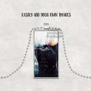 May include: A silver chain necklace with a rectangular pendant featuring a black cat with colorful abstract background.