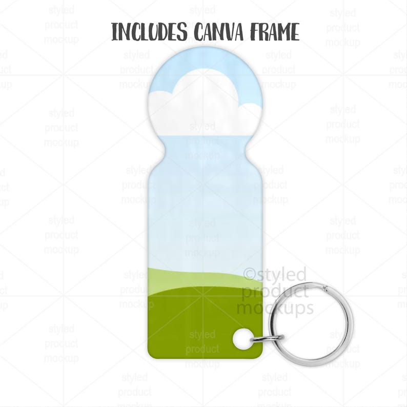 May include: A keychain with a sky and cloud design. The top portion features a blue sky with white clouds, transitioning to a light blue and green landscape. The text "INCLUDES CANVA FRAME" is at the top. A silver key ring is attached.
