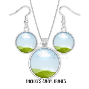 May include: A silver necklace and earring set. Each piece has a round pendant with a landscape design of a blue sky, white cloud, and green hills. The text "INCLUDES CANVA FRAMES" is at the bottom. The earrings have hook closures.