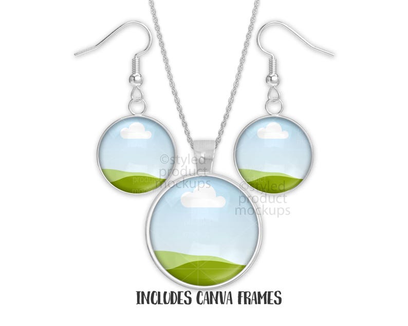 May include: A silver necklace and earring set. Each piece has a round pendant with a landscape design of a blue sky, white cloud, and green hills. The text "INCLUDES CANVA FRAMES" is at the bottom. The earrings have hook closures.
