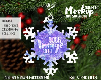 May include: White snowflake ornament mockup with a purple and blue watercolour design. The text "Your Image Here" is written on the ornament. The ornament is on a green background with red berries.