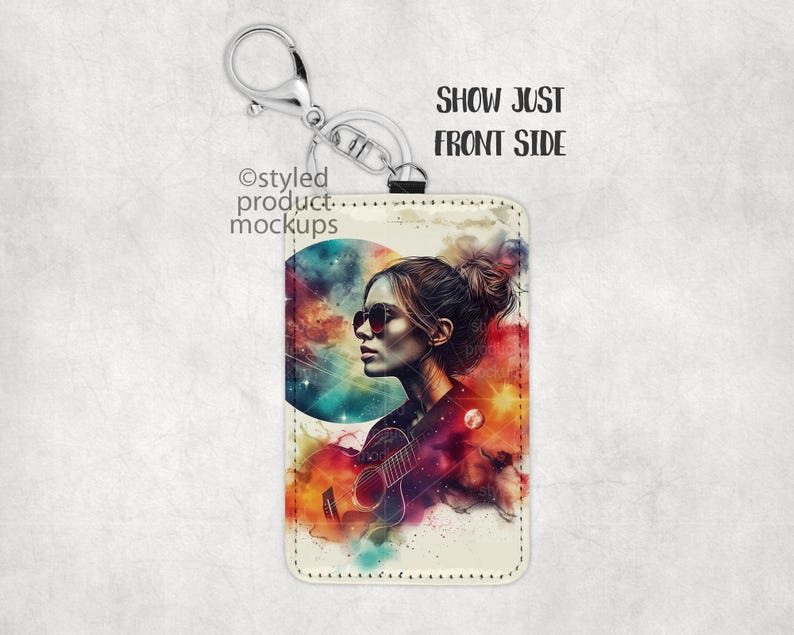May include: A white leather keychain with a colorful abstract design featuring a woman with sunglasses and a guitar. The design includes a large circle with a galaxy-like pattern.