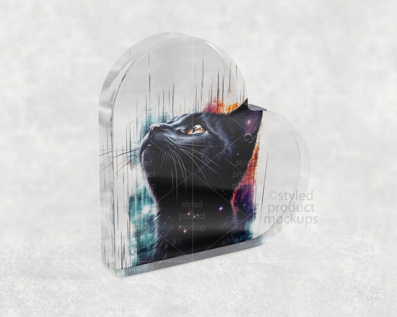 Pu&ograve; includere: Un blocco acrilico a forma di cuore con un design di gatto nero. Il gatto guarda in alto, con una rappresentazione dettagliata della pelliccia e dei baffi. Lo sfondo presenta una miscela di colori, tra cui blu, rosso e viola.