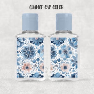 May include: Two clear, rectangular bottles with light blue caps. The bottles feature a floral design with blue and peach flowers on a white background. The text "CHANGE CAP COLOR" is above the bottles.