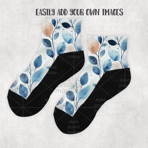 K&ouml;nnte beinhalten: Ein Paar Socken mit einem botanischen Design. Die Socken haben einen wei&szlig;en Hintergrund mit blau und pfirsichfarbenen Bl&auml;ttern und schwarzen Fersen und Zehen. Der Text "EASILY ADD YOUR OWN IMAGES" steht oben.
