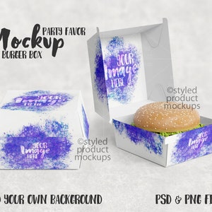 May include: A white burger box mockup with a watercolor design in shades of purple and blue. The box is open and a hamburger is inside. The text "Your Image Here" is printed on the box.