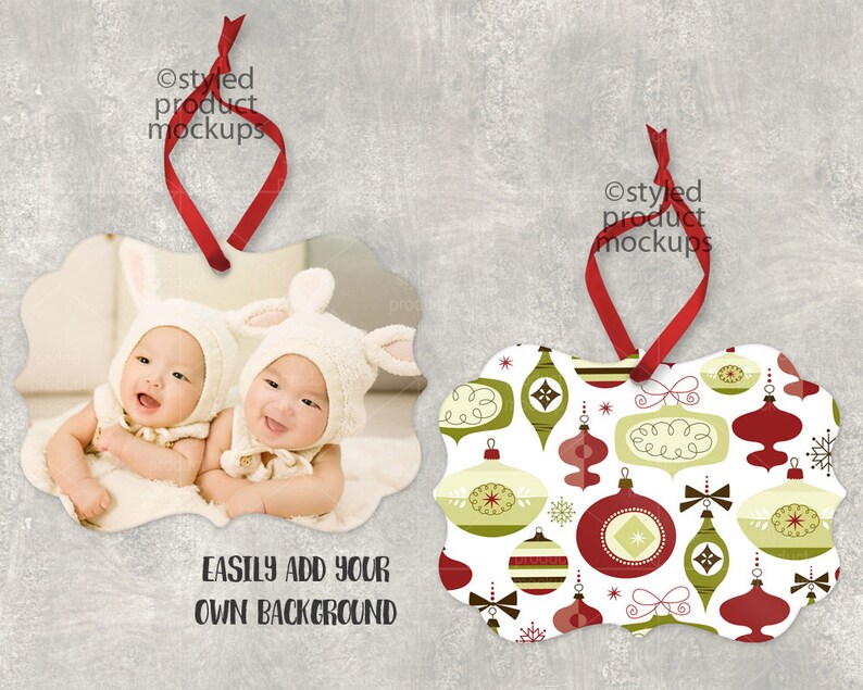 May include: Two baby ornaments with a photo of twins wearing bunny ears and white hats. The ornaments are white with a scalloped edge and a red ribbon for hanging. The text "EASILY ADD YOUR OWN BACKGROUND" is printed below the ornaments.