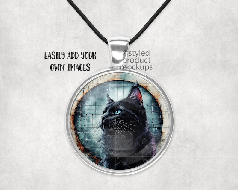 May include: A silver pendant necklace featuring a black cat image within a round glass cabochon. The cat has blue eyes and is gazing to the left. The background is an abstract design in shades of blue and grey.
