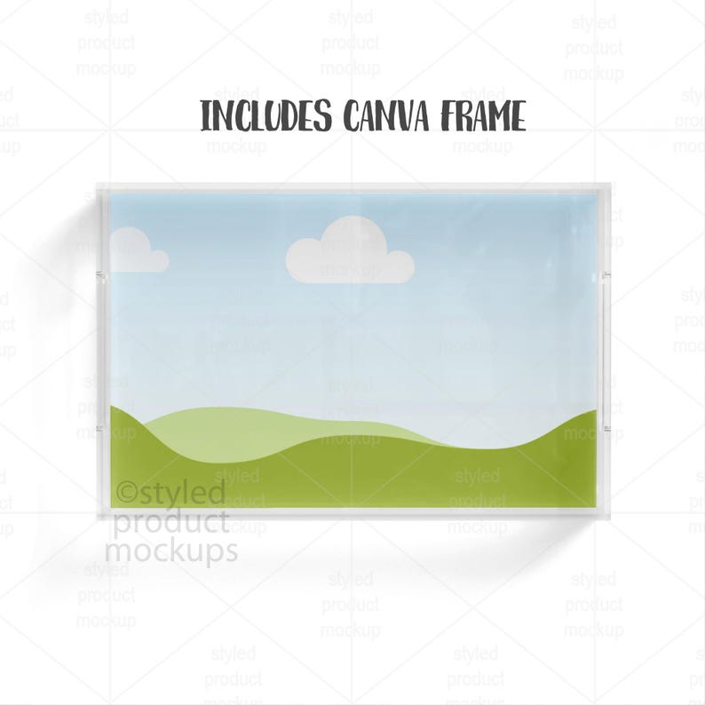 May include: A rectangular clear acrylic frame with a landscape scene inside. The scene features a blue sky with two white clouds and green rolling hills. The text "INCLUDES CANVA FRAME" is printed at the top.