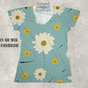 Op de afbeelding: Een lichtblauw V-hals T-shirt met een madeliefjespatroon, met grote witte en gele bloemen. Het shirt heeft korte mouwen en de tekst "EASILY ADD YOUR OWN BACKGROUND" is zichtbaar.