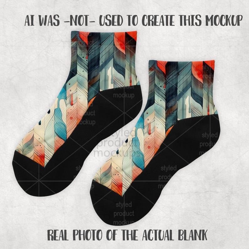 K&ouml;nnte beinhalten: Ein Paar Kn&ouml;chelsocken mit einem farbenfrohen Federdesign. Die Socken haben eine schwarze Ferse und Zehen, mit einem Muster im Aquarellstil in Blau-, Orange- und Cremet&ouml;nen. Der Text "AI WAS -NOT- USED TO CREATE THIS MOCKUP" und "REAL PHOTO OF THE ACTUAL BLANK" sind sichtbar.