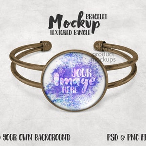 Könnte beinhalten: Ein bronzefarbenes Armreif-Mockup mit einem runden, zentralen Designbereich. Die Mitte zeigt einen weißen Kreis mit dem Text "YOUR IMAGE HERE" über einem blau-violetten Hintergrund im Aquarellstil. Die Wörter "Mockup" und "TEXTURED BANGLE" stehen darüber.