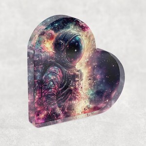 Pu&ograve; includere: Vassoio decorativo a forma di cuore con un astronauta in tuta spaziale su uno sfondo di galassia vibrante. L'opera d'arte presenta una miscela di tonalit&agrave; viola, blu e arancioni, creando un tema cosmico. Il vassoio &egrave; realizzato in materiale lucido.