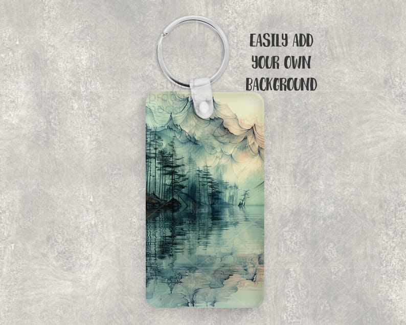 K&ouml;nnte beinhalten: Ein rechteckiger Schl&uuml;sselanh&auml;nger mit einem Landschaftsdesign mit einem See und B&auml;umen in Blau- und Gr&uuml;nt&ouml;nen. Der Schl&uuml;sselanh&auml;nger hat einen silbernen Metallring und den Text "EASILY ADD YOUR OWN BACKGROUND".