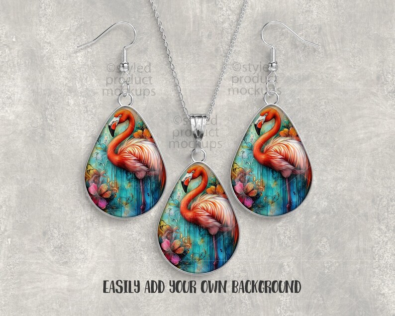 May include: A jewelry set featuring a flamingo design. The set includes a necklace and a pair of earrings. Each piece has a teardrop shape with a silver-colored border. The flamingo is depicted with pink and orange feathers against a teal and floral background.