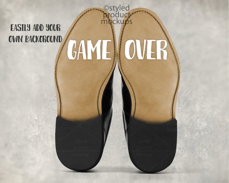 May include: A pair of black leather dress shoes with the words "GAME OVER" printed in white on the soles. The image includes the text "EASILY ADD YOUR OWN BACKGROUND" and "styled product mockups".