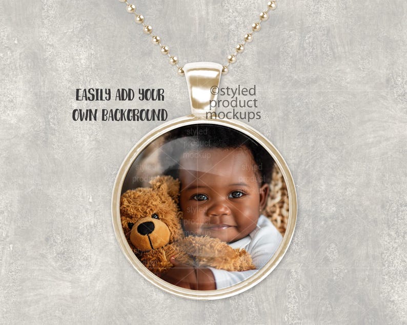 May include: A gold chain necklace with a round pendant featuring a photo of a young child holding a teddy bear. The pendant has a clear glass front and a gold metal frame.