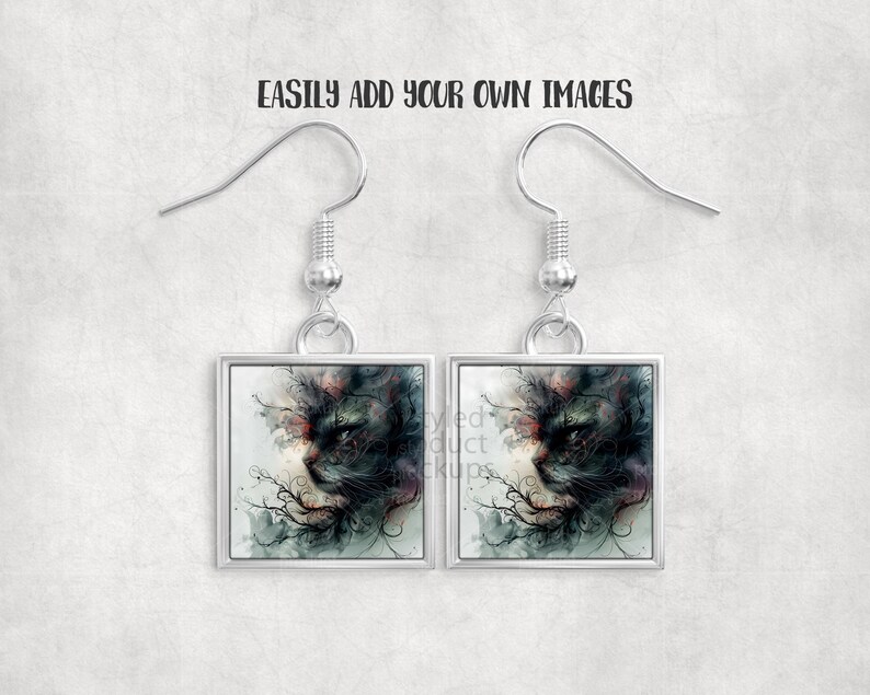 Pu&ograve; includere: Orecchini quadrati color argento con un design dettagliato di una faccia di gatto. Il volto del gatto &egrave; raffigurato in tonalit&agrave; di nero, verde e rosso, con dettagli intricati. Gli orecchini hanno una chiusura a gancio. Il testo "EASILY ADD YOUR OWN IMAGES" &egrave; in alto.