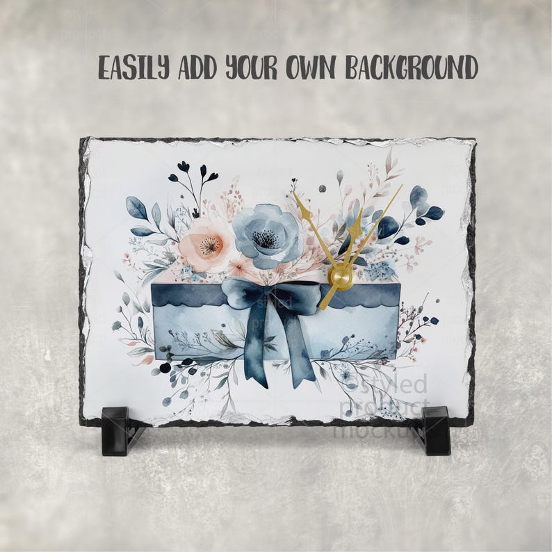 Puede incluir: Un reloj decorativo de pizarra con un dise&ntilde;o floral en acuarela. Presenta flores azules y melocot&oacute;n, una caja de regalo azul y un lazo azul oscuro. El reloj tiene manecillas doradas y el texto "EASILY ADD YOUR OWN BACKGROUND".