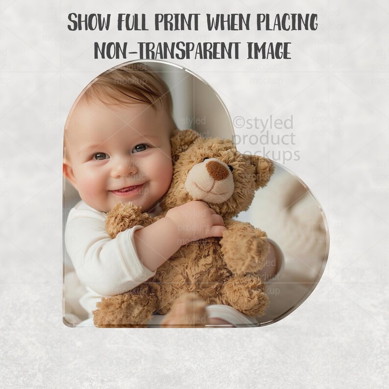 May include: A smiling baby in a white onesie holds a brown teddy bear. The image is in a heart-shaped frame. Text at the top reads: SHOW FULL PRINT WHEN PLACING NON-TRANSPARENT IMAGE.