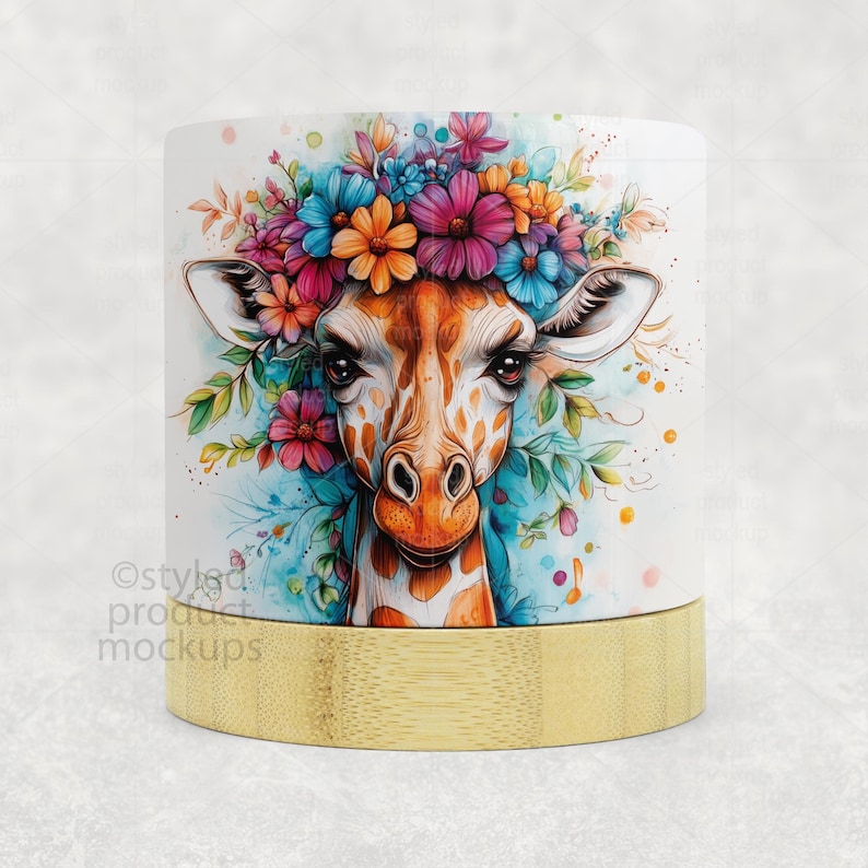 Op de afbeelding: Witte keramische mok met een aquarel illustratie van een giraffe met een bloemenkrans. De giraffe heeft oranje en bruine vlekken, en de bloemen zijn roze, blauw en oranje. De basis van de mok is lichtbruin bamboe.