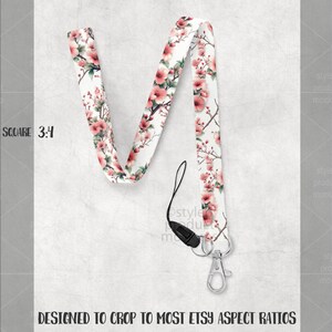 May include: A white lanyard with a floral pattern of pink blossoms and green leaves. The lanyard has a black clasp and a silver-colored metal clip. The text "DESIGNED TO CROP TO MOST ETSY ASPECT RATIOS" is at the bottom.