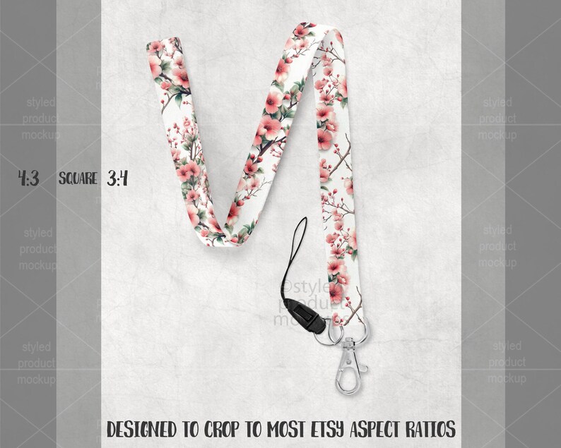 May include: A white lanyard with a floral pattern of pink blossoms and green leaves. The lanyard has a black clasp and a silver-colored metal clip. The text "DESIGNED TO CROP TO MOST ETSY ASPECT RATIOS" is at the bottom.