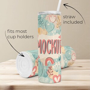 May include: A pair of insulated tumblers with a whimsical floral and heart pattern in pastel colors. One tumbler is upright with a straw, the other is lying down. Text on the tumbler reads "MOCKUP". The text "straw included" and "fits most cup holders" are also visible.