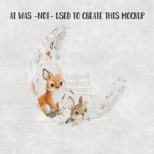 May include: A clear, crescent-shaped decorative item featuring a watercolor illustration of a fox and a rabbit. The artwork includes floral elements in orange and brown tones. The text "AI WAS -NOT- USED TO CREATE THIS MOCKUP" is visible at the top.