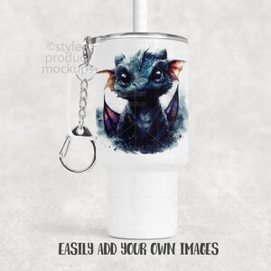 May include: White tumbler featuring a watercolor illustration of a blue and purple dragon with large eyes and orange ears. The tumbler has a silver keychain attached. Text at the bottom reads: EASILY ADD YOUR OWN IMAGES.