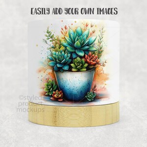 Op de afbeelding: Een witte cilindrische productmockup met een aquarel illustratie van vetplanten in een blauwe pot. De basis is gemaakt van bamboe. De tekst "EASILY ADD YOUR OWN IMAGES" staat bovenaan.