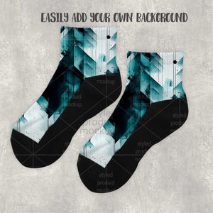 K&ouml;nnte beinhalten: Ein Paar Socken mit einem geometrischen Design in T&uuml;rkis, Wei&szlig; und Schwarz. Der obere Teil hat ein t&uuml;rkisfarbenes und wei&szlig;es Muster, w&auml;hrend der untere Teil und die Zehen schwarz sind. Der Text "EASILY ADD YOUR OWN BACKGROUND" steht oben.
