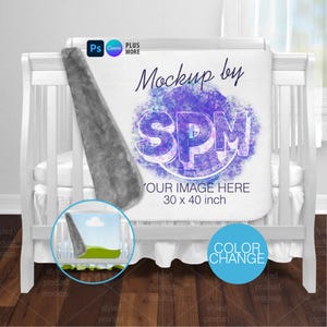 May include: A white baby blanket with the text "Mockup by SPM" and "YOUR IMAGE HERE 76 x 102 cm". The blanket is draped over a white crib. A gray plush material is attached to the blanket.