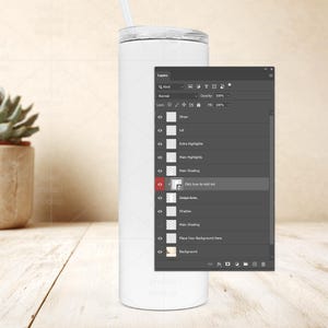 May include: A white, cylindrical tumbler with a clear lid and straw. The tumbler is shown in a product mockup setting, with a digital interface overlay. The interface shows layers for design elements.