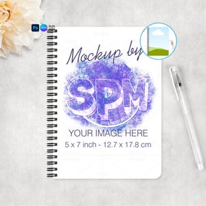 May include: A white spiral-bound notebook with the text "Mockup by SPM" and "YOUR IMAGE HERE". The notebook is 5 x 7 inches (12.7 x 17.8 cm). A clear pen rests on the right side. A flower is in the upper left corner.