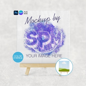 Puede incluir: Una maqueta de lienzo blanco con el texto "Mockup by SPM" en una fuente estilizada. El lienzo está sobre un pequeño caballete de madera. El texto "YOUR IMAGE HERE" está debajo del logotipo de SPM. Un pequeño círculo con una pintura de paisaje está en la parte inferior derecha.