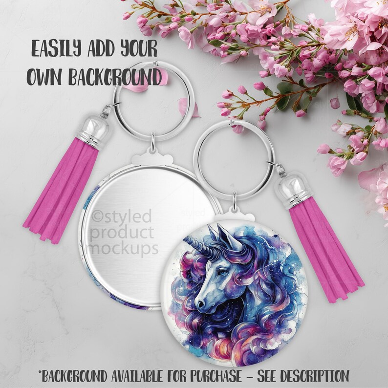 May include: Two round keychains with silver-tone metal rims and pink tassels. One keychain features a watercolor unicorn design in blue, purple, and pink. The text "EASILY ADD YOUR OWN BACKGROUND" is visible. "BACKGROUND AVAILABLE FOR PURCHASE - SEE DESCRIPTION" is also visible.