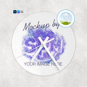 May include: A round wall clock featuring a white face with a central purple watercolor splash design. The text reads Mockup by SPM and YOUR IMAGE HERE. Three plain white clock hands are positioned in the center of the circular clock face.
