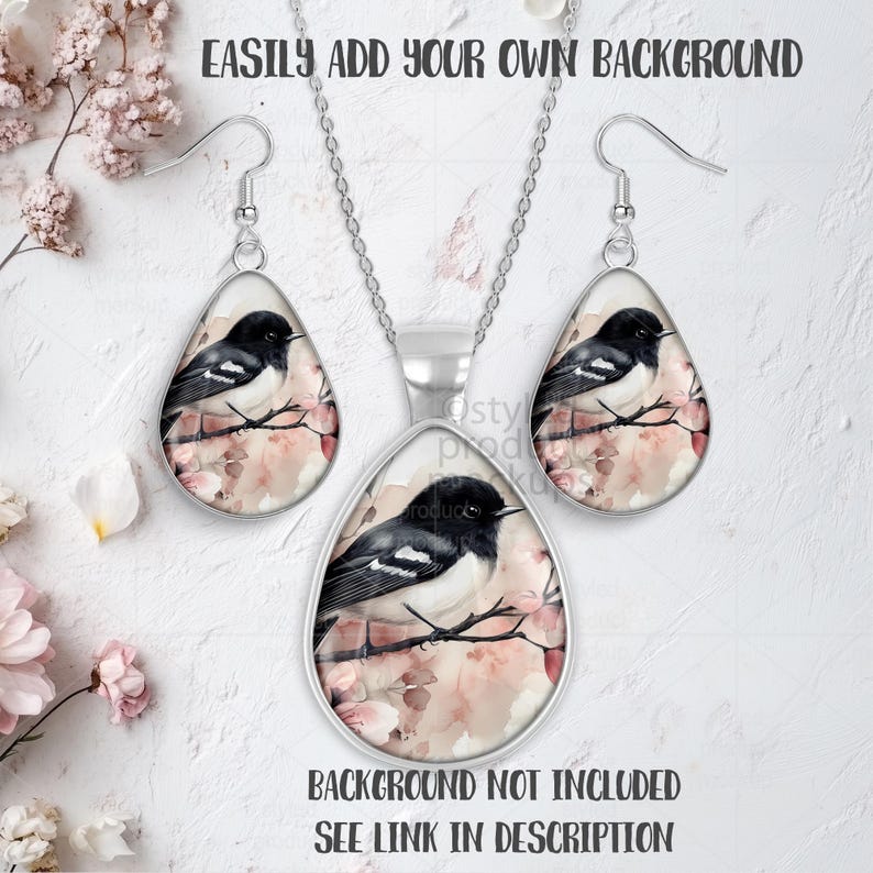 May include: A silver-toned jewelry set featuring a pendant and matching earrings. Each piece showcases a black and white bird perched on a branch with pink blossoms. The text "EASILY ADD YOUR OWN BACKGROUND" and "BACKGROUND NOT INCLUDED SEE LINK IN DESCRIPTION" are visible.