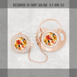 May include: A rose gold baby pacifier and matching clip. Both feature a floral design with red, orange, and yellow flowers. The pacifier and clip are adorned with clear rhinestones around the floral center.