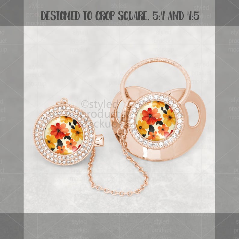 May include: A rose gold baby pacifier and matching clip. Both feature a floral design with red, orange, and yellow flowers. The pacifier and clip are adorned with clear rhinestones around the floral center.