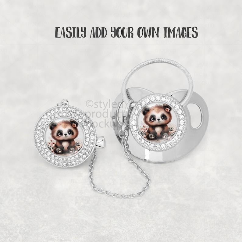 May include: A silver baby pacifier and clip set. Each piece features a round design with a cute panda bear illustration surrounded by clear rhinestones. A small chain connects the clip to the pacifier.