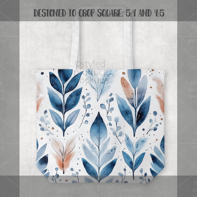 Pu&ograve; includere: Borsa tote bianca con un design ad acquerello di foglie e rami blu e color pesca. La borsa ha manici bianchi e il testo "DESIGNED TO CROP SQUARE. 5:4 AND 4:5".