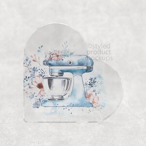 May include: A light blue stand mixer illustration with a silver mixing bowl, adorned with watercolor floral accents in pink and blue. The design is set against a soft, neutral background, evoking a sense of vintage charm and culinary artistry.