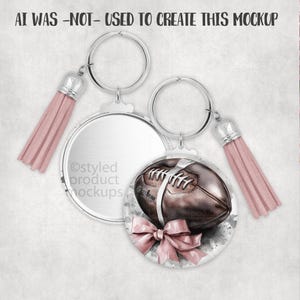 May include: Two keychains with silver rings and pink tassels. One keychain has a blank, round, silver pendant. The other keychain has a round pendant with a brown football design and a pink bow. The text "AI WAS -NOT- USED TO CREATE THIS MOCKUP" is at the top.