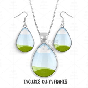 May include: A silver-toned necklace and earring set. The pendant and earrings are teardrop-shaped with a landscape design featuring a blue sky, white clouds, and green hills. The text "INCLUDES CANVA FRAMES" is at the bottom.