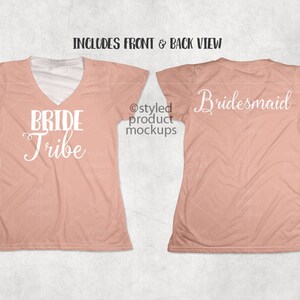 Op de afbeelding: Twee perzikkleurige t-shirts, voor- en achteraanzicht, met witte tekst. Het shirt aan de voorkant leest "BRIDE Tribe" in een scriptlettertype en het shirt aan de achterkant zegt "Bridesmaid". De shirts hebben een V-hals.